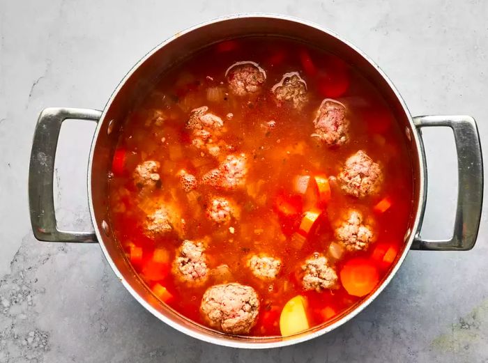 Aerial view of meatballs and vegetables cooking in broth for albondigas soup