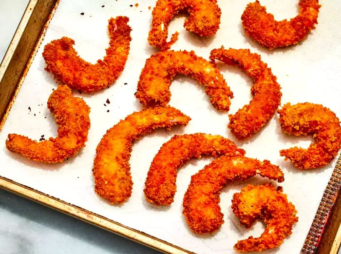 A baking sheet lined with paper towels holding crispy Japanese-style fried shrimp.