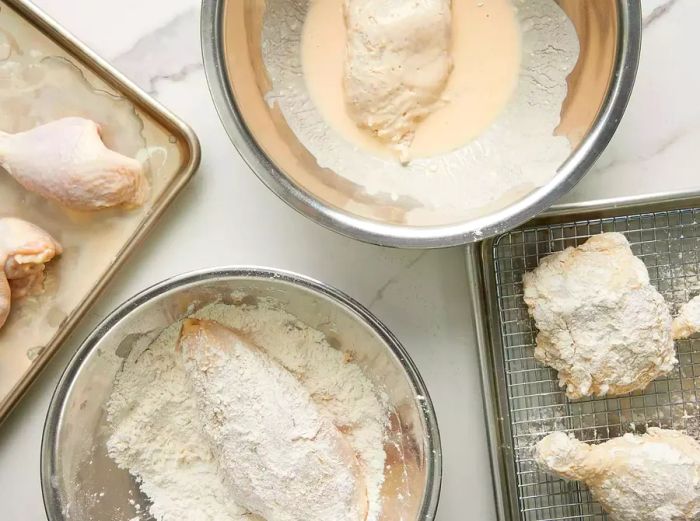 Top-down view of a breading station for preparing chicken pieces for Nashville hot chicken