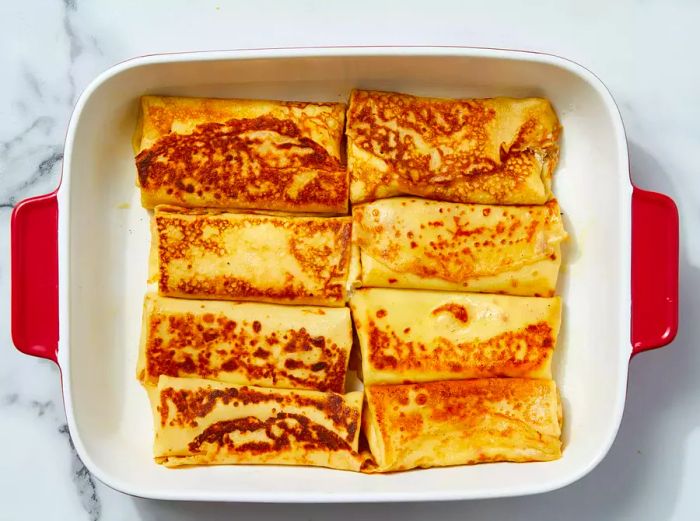 Blintzes placed in the baking dish, then baked until the filling is firm.