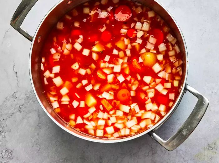 Aerial view of a pot filled with broth and vegetables simmering for albondigas soup