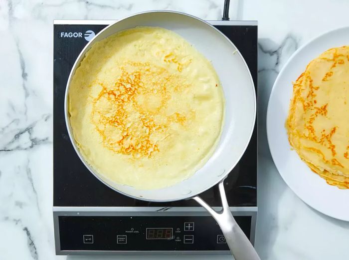 Flip the crêpe, cook the other side briefly, then transfer it to a plate.