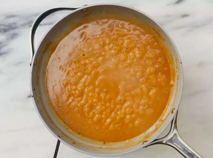 Overhead view of beef broth gravy simmering in a skillet for the Swedish Meatballs (Svenska Köttbullar) recipe.