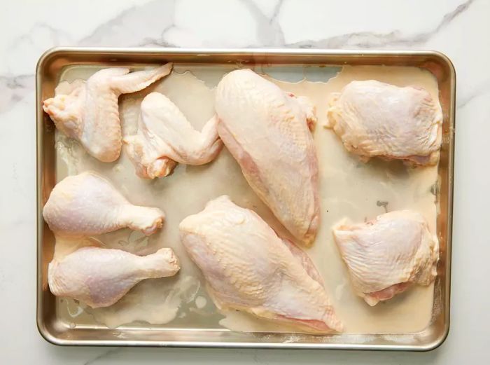 Top-down view of chicken pieces soaking in marinade for Nashville hot chicken