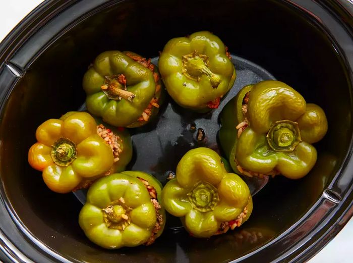 Aerial shot of a slow cooker filled with perfectly cooked stuffed green peppers.