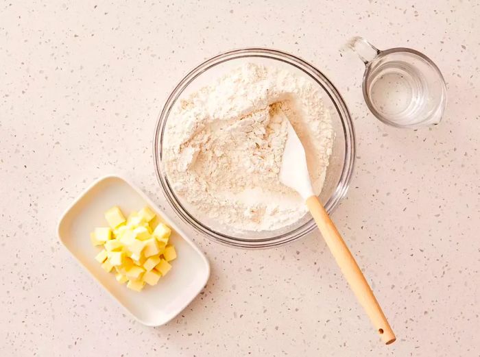 A bowl containing flour, baking powder, and salt, being stirred with a spatula.