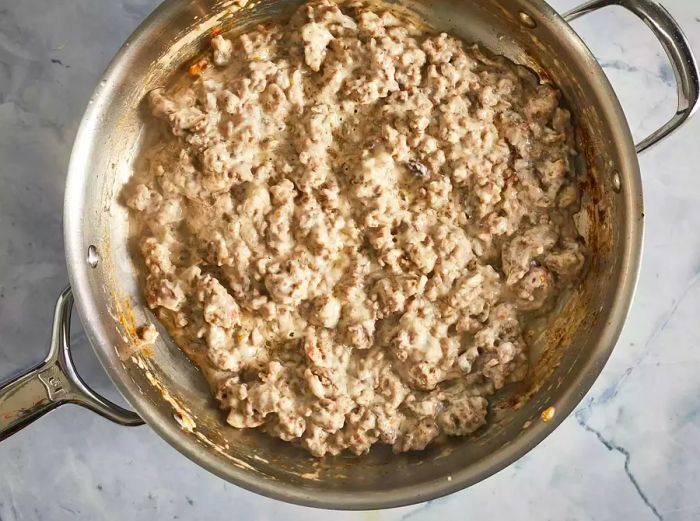 Condensed soup, garlic powder, and ground beef simmering together in a skillet.