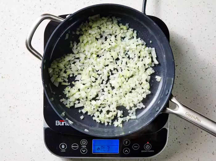 A skillet with chopped onions sizzling in hot oil.