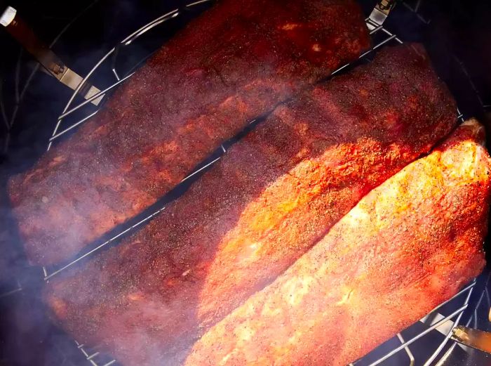 The ribs are placed in the smoker, cooking for one hour.