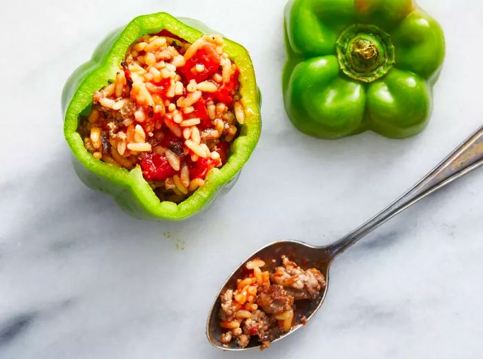 Aerial view of a green pepper being carefully stuffed with the filling.