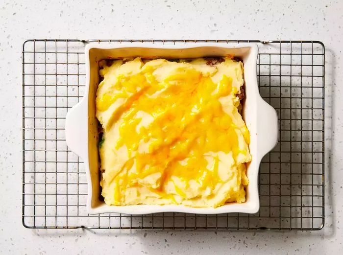 A baking dish of Ground Beef Shepherd's Pie, with a golden mashed potato topping and melted cheese.