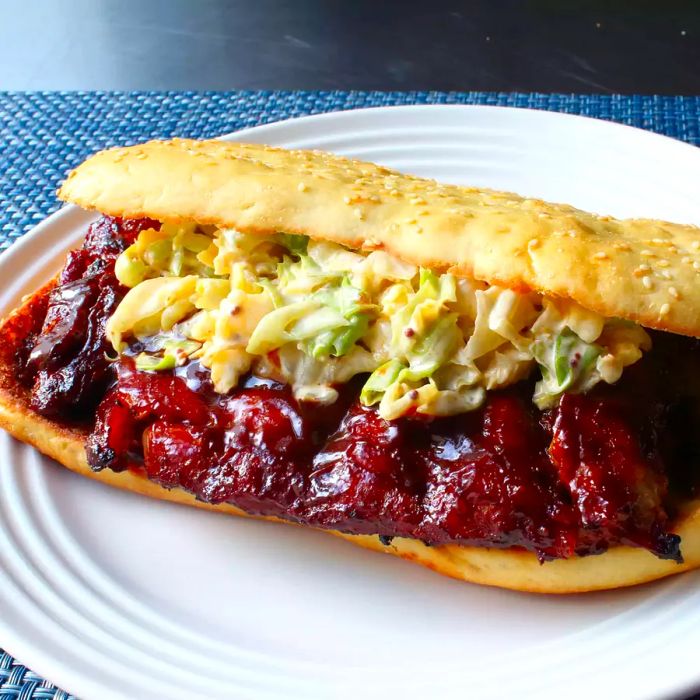 Close-up of a McRib Sandwich topped with slaw, served on a white plate