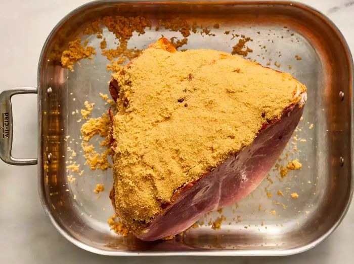 Ham in the roasting pan, coated with a layer of brown sugar