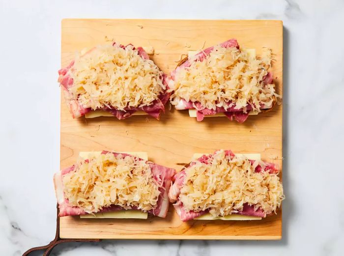 Bread stacked with Swiss cheese, corned beef, and sauerkraut