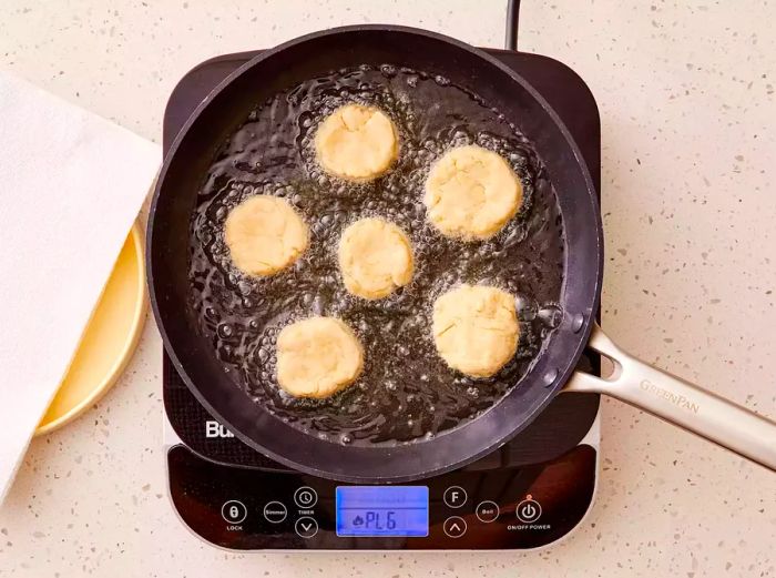 A pan with Jamaican dumplings sizzling in hot oil