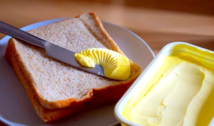 spreading margarine onto a slice of bread