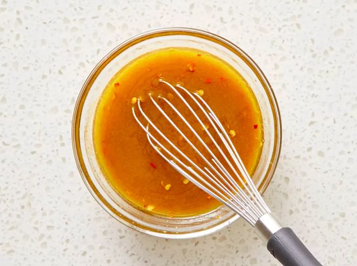 overhead view of quinoa salad dressing being whisked in a bowl