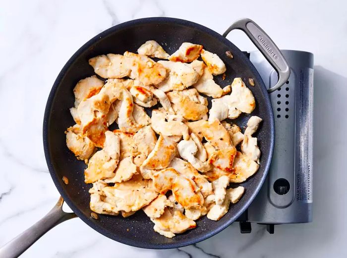 A large skillet with browned pieces of chicken