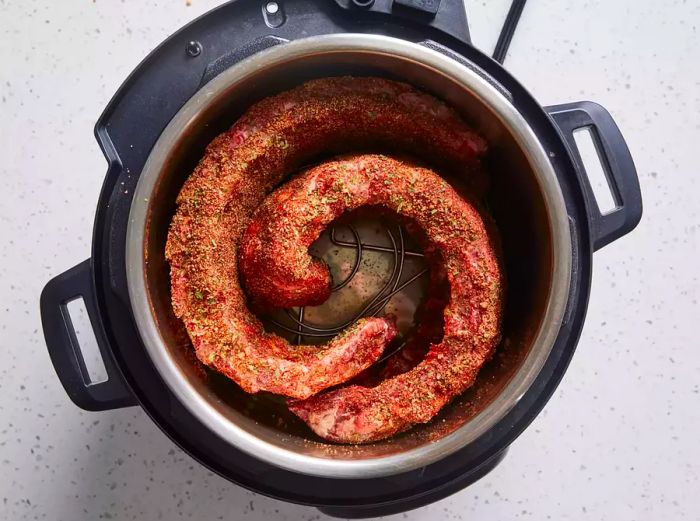 Ribs placed into the Instant Pot, curling around the edge of the pot.