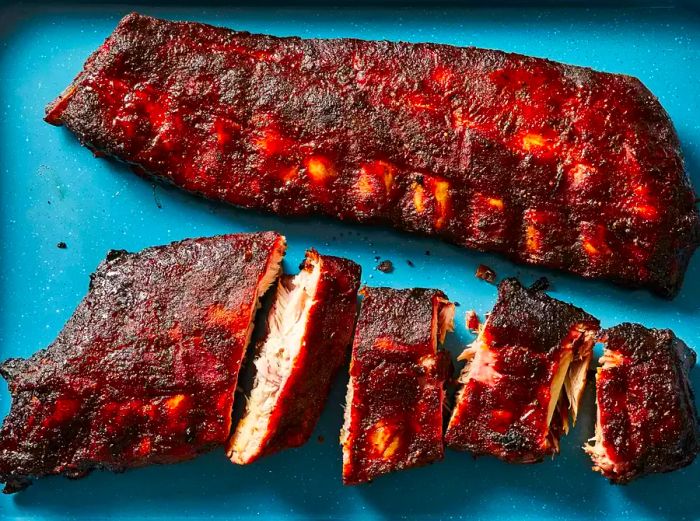 A close-up view of two racks of sweet smoked pork ribs, with some slices ready to be served.