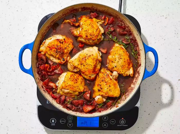 An overhead shot of chicken thighs added back into the skillet.