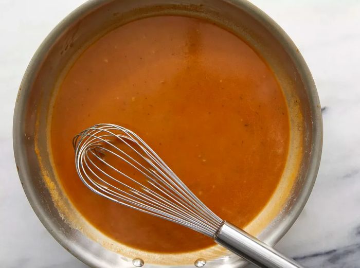 Broth and browning sauce combined with seasonings, stirring until the gravy begins to thicken.