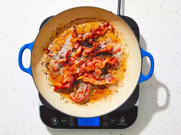 An overhead shot of bacon sizzling in a skillet