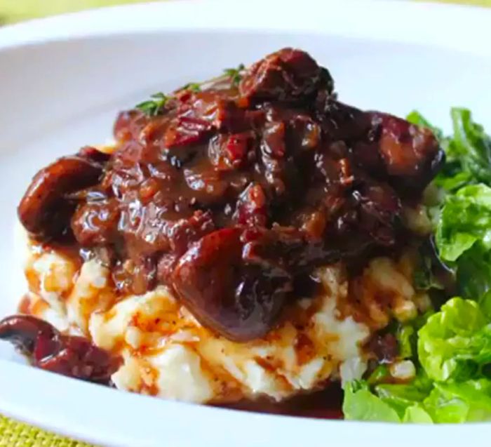 A serving of chicken and mushrooms over a creamy bed of mashed potatoes