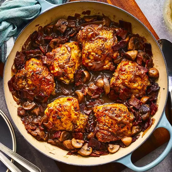 A top-down view of Chef John's Coq au Vin simmering in a cast iron Dutch oven.