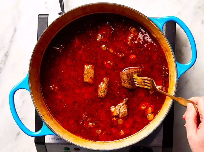 The mixture is simmering, and a fork easily slides into the tender meat.