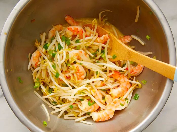 Top-down view of a mixing bowl filled with ingredients for shrimp egg foo young