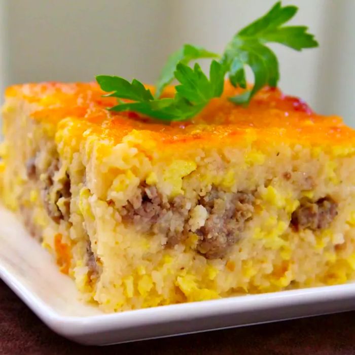 A close-up of a slice of Southern Grits Casserole, beautifully garnished with fresh herbs, served on a white plate.