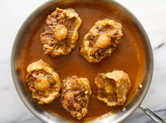 Oxtails added to the skillet, coated with the gravy mixture.