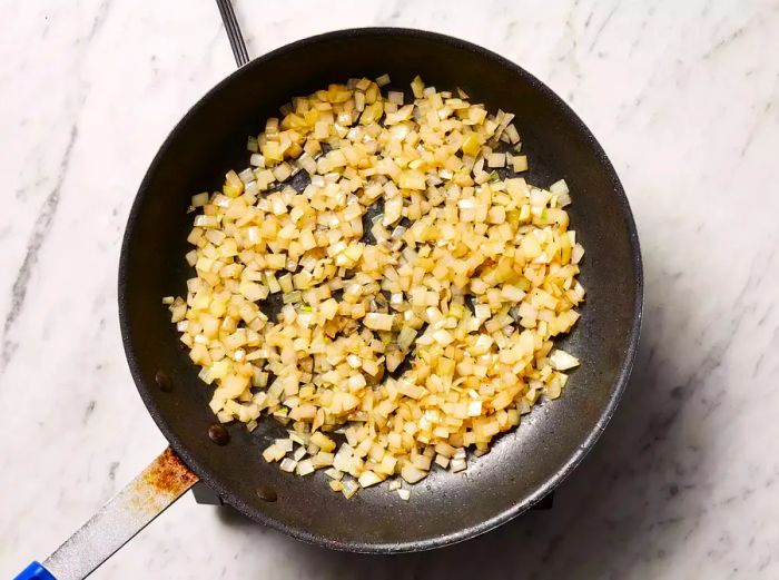 Onions cooking in the skillet with the reserved drippings, softening as they cook.