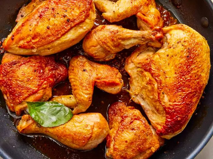 Bird's-eye view of chicken adobo cooking in a large skillet