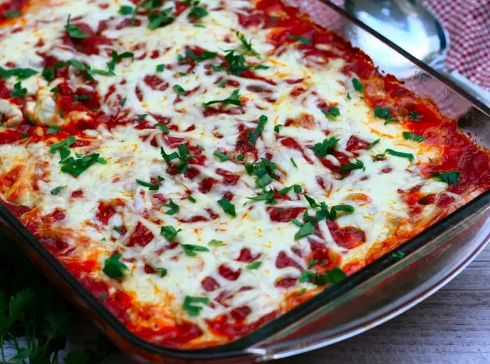 A cheesy baked spaghetti casserole topped with melted mozzarella and garnished with chopped parsley.