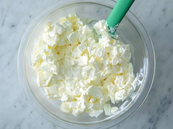 Sour cream, cream cheese, and onion blended together in a bowl.