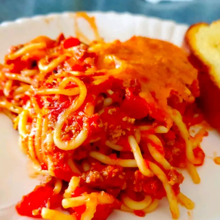 A close-up shot of the Basic Baked Spaghetti served on a white plate, accompanied by a slice of toast.