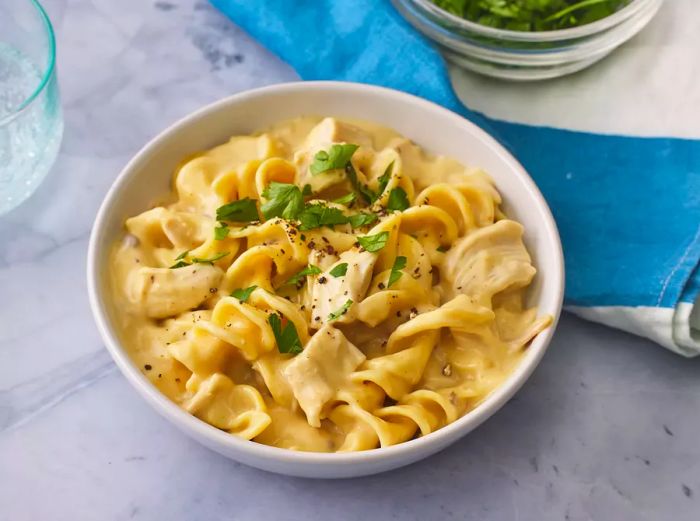 A bowl of incredibly easy chicken and noodles topped with fresh herbs.