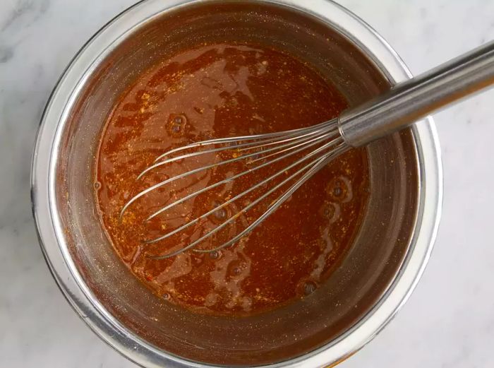 Overhead shot of a mixing bowl with ingredients being whisked together to make Marsala gravy for the roast