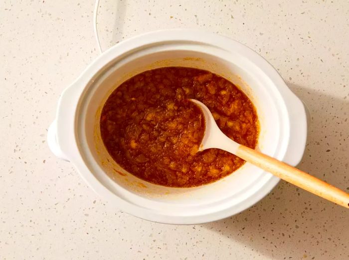 A slow cooker filled with spiced, chunky applesauce