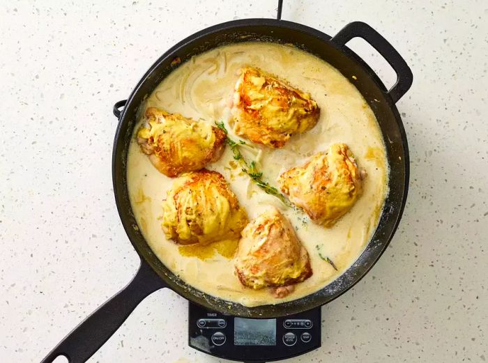 Dijon Chicken cooking in sauce in a cast iron skillet on the stove