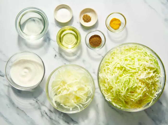 Ingredients for cabbage slaw arranged on a marble countertop.