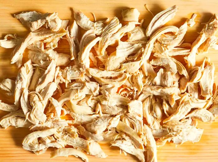 Chunks of chicken breast resting on a cutting board, ready to be added to the dish.