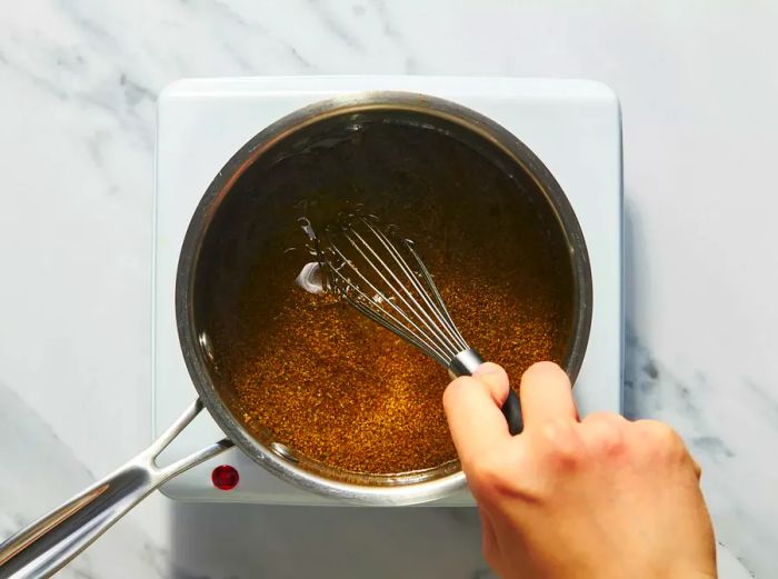 Stirring the dressing ingredients for cabbage slaw in a saucepan.