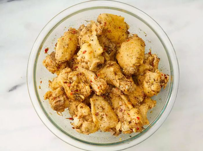 Chicken wings coated in seasoning, placed in a bowl