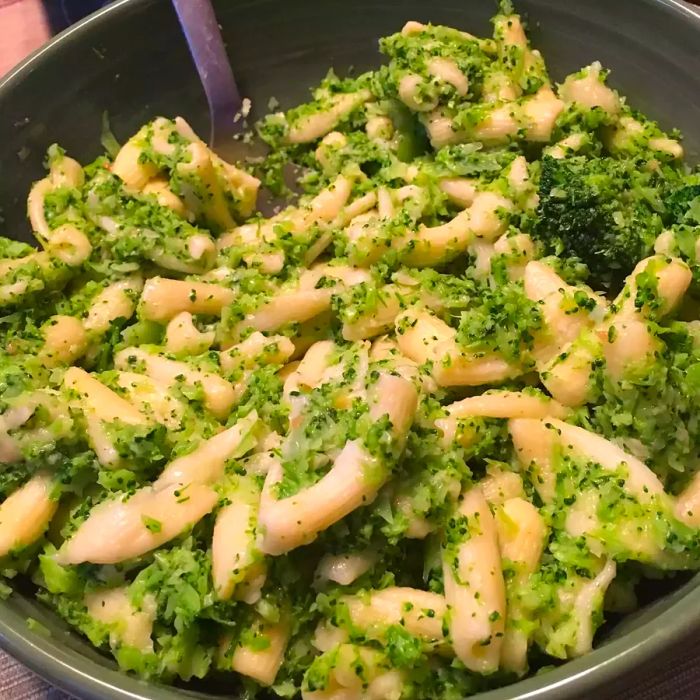 Close-up shot of cavatelli and broccoli sautéing in a pan with a spatula