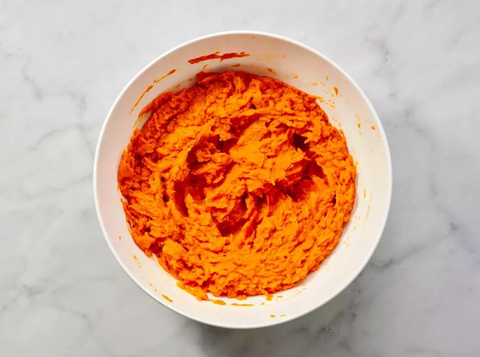 A bowl filled with mashed sweet potatoes, ready for mixing.