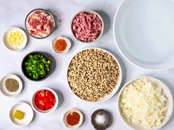 A bird's-eye view of various bowls and containers filled with black-eyed pea ingredients.