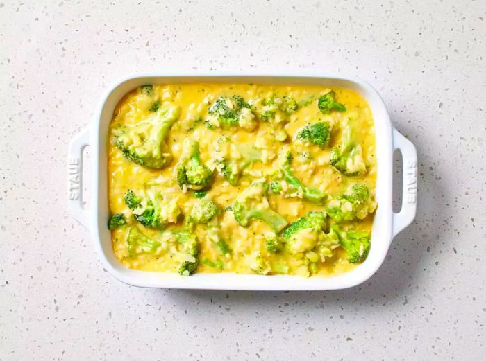 A baking dish filled with rice and broccoli covered in a cheesy sauce